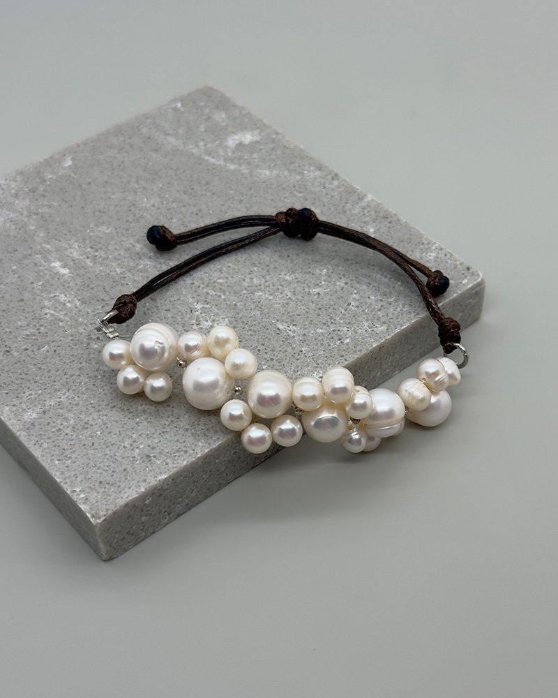 Pulsera ajustable trenzada con hilo café y perlas de diferentes tamaños