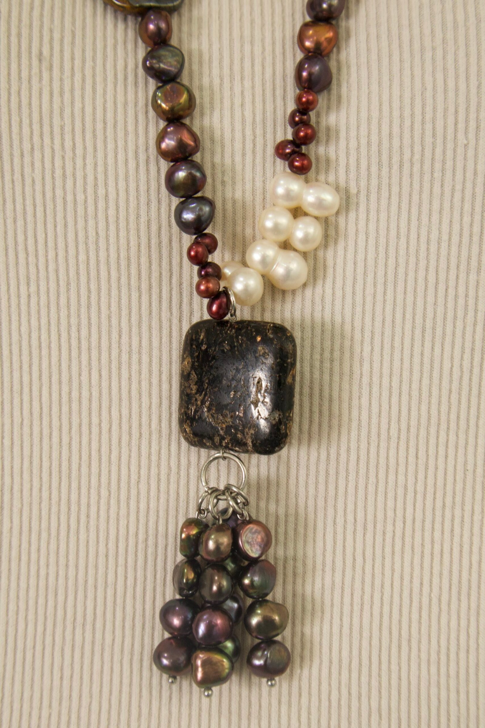 Collar con perlas cultivadas blancas y oscuras, piedras naturales en tonos tierra y rojizos, y un dije central de piedra oscura - Imagen 5