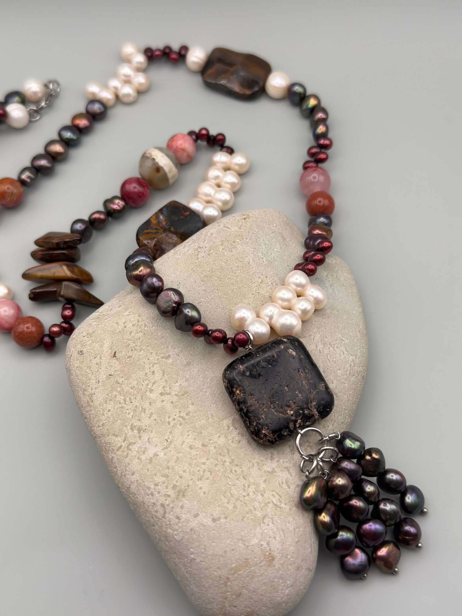 Collar con perlas cultivadas blancas y oscuras, piedras naturales en tonos tierra y rojizos, y un dije central de piedra oscura - Imagen 3
